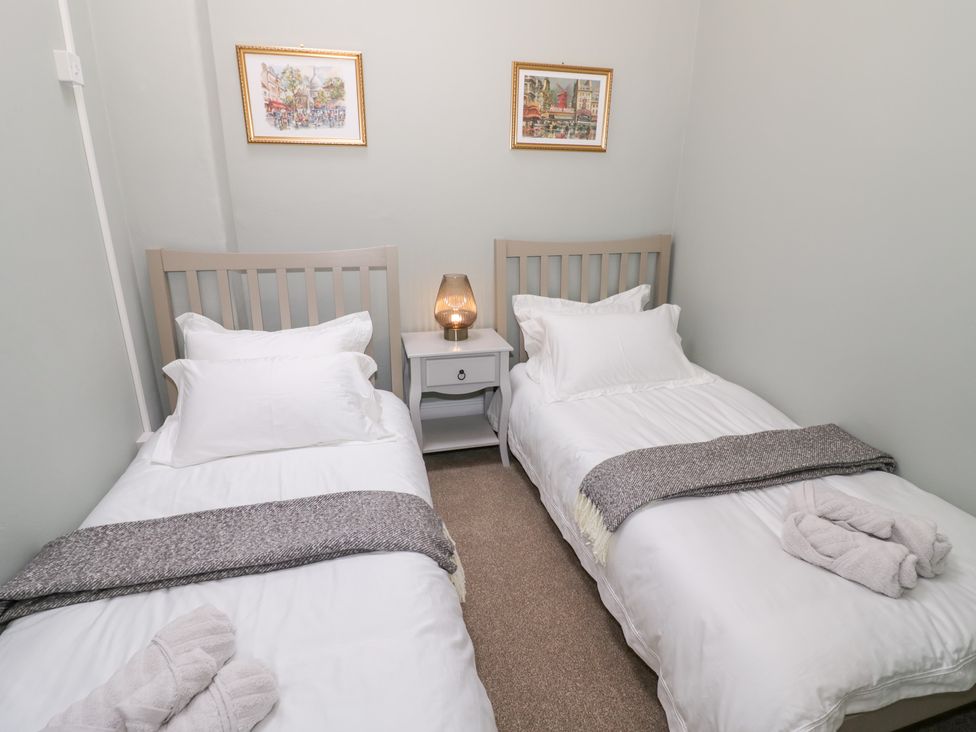 A bedroom with twin beds and a nightstand at 12 Montpellier Arcade in Cheltenham