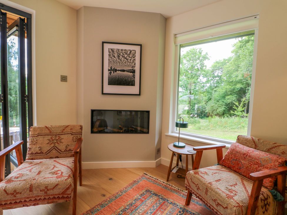 A snug area with a fireplace and chairs at Lakeside Lodge in Witherenden Hill near Burwash