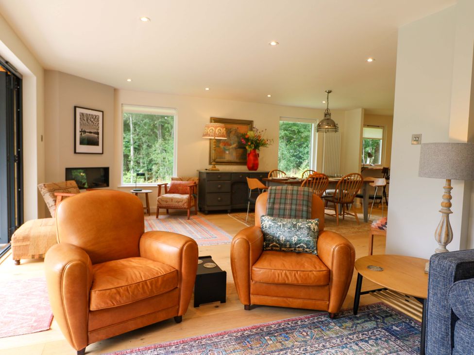 A living room with armchairs and a dining area at Lakeside Lodge, Witherenden Hill near Burwash