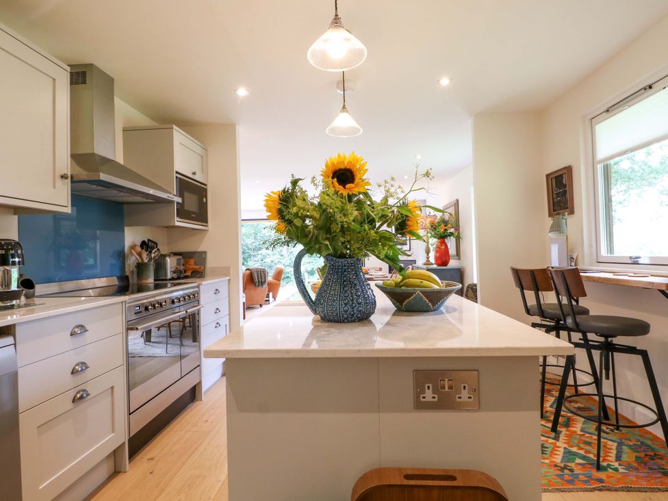 A kitchen with a countertop island and flowers at Lakeside Lodge in Witherenden Hill near Burwash