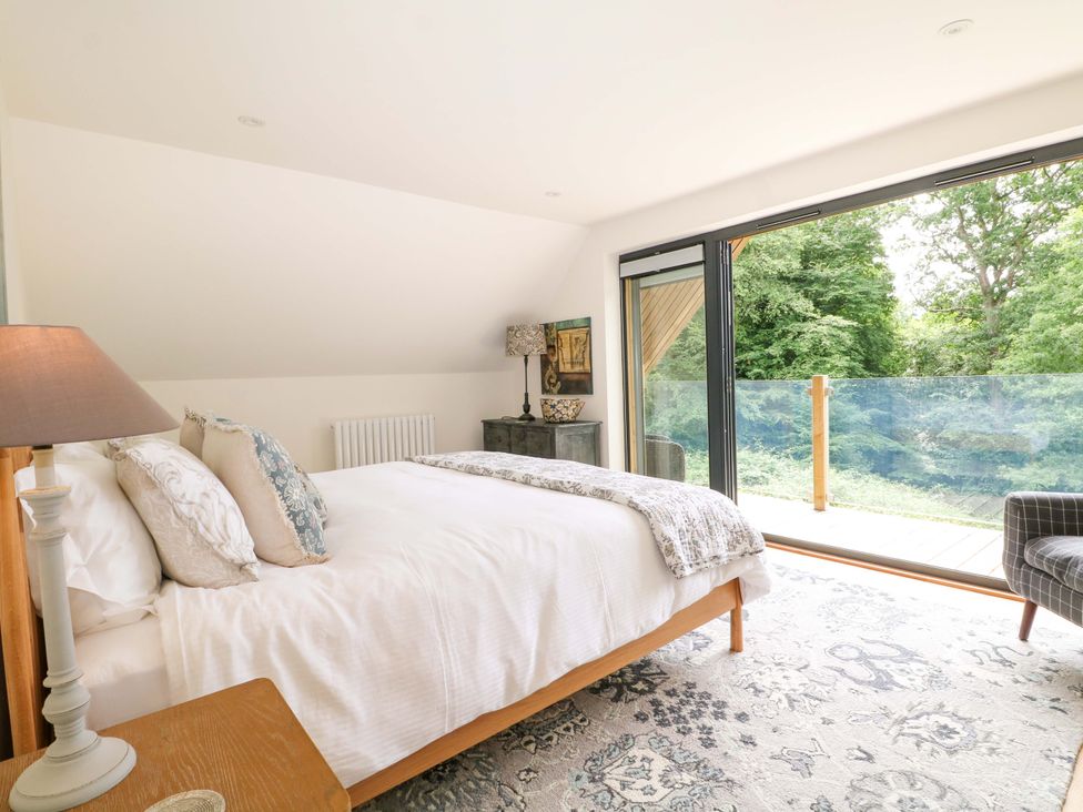A bedroom with a bed and window overlooking a garden at Lakeside Lodge Witherenden Hill near Burwash