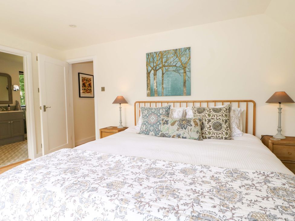A bedroom with a large bed and artwork on the wall at Lakeside Lodge near Witherenden Hill