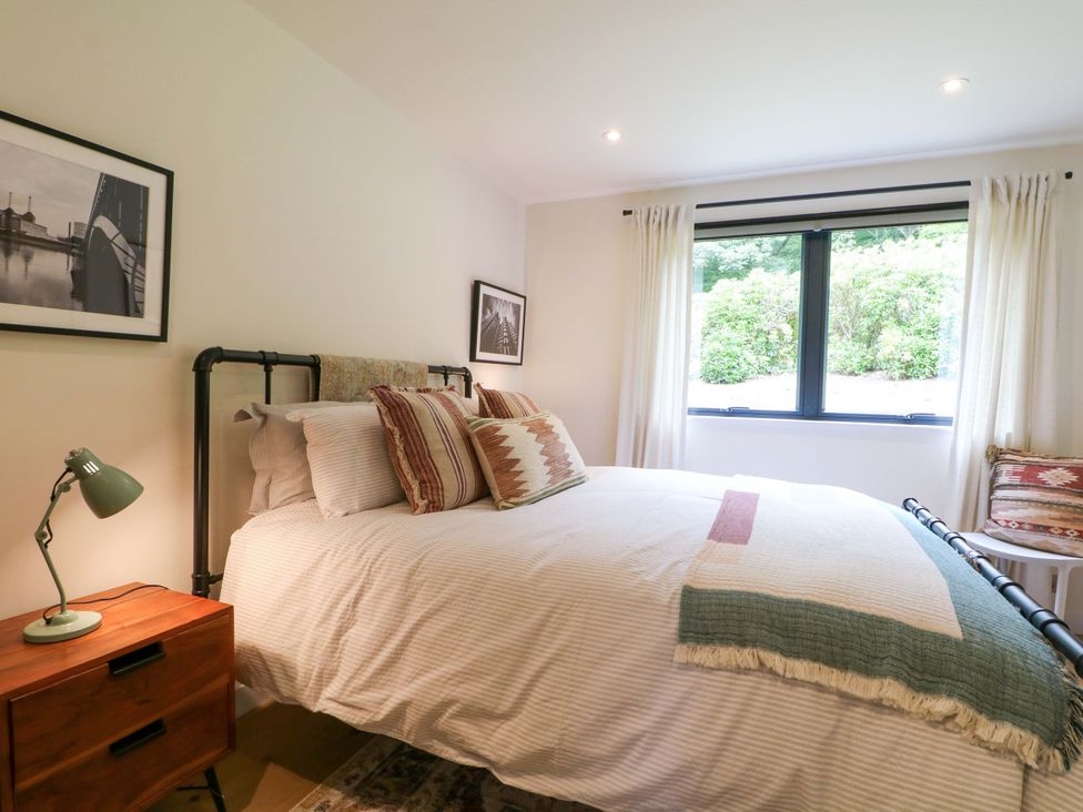 A bedroom with a bed and bedside table at Lakeside Lodge near Burwash