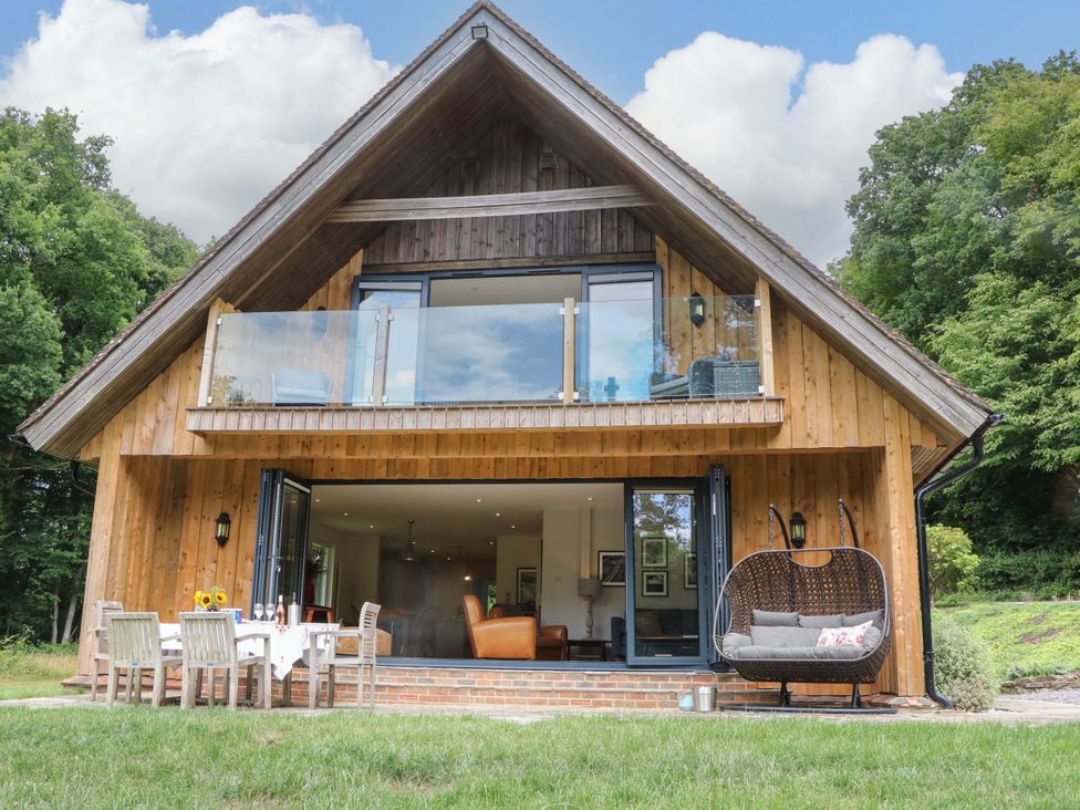 A wooden house with a deck and outdoor furniture at Lakeside Lodge Witherenden Hill near Burwash