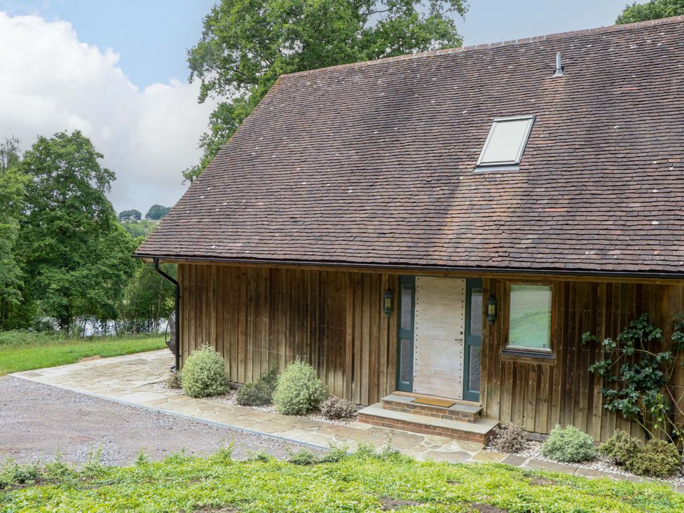 An exterior view of a wooden building with a door and windows at Lakeside Lodge in Witherenden Hill near Burwash
