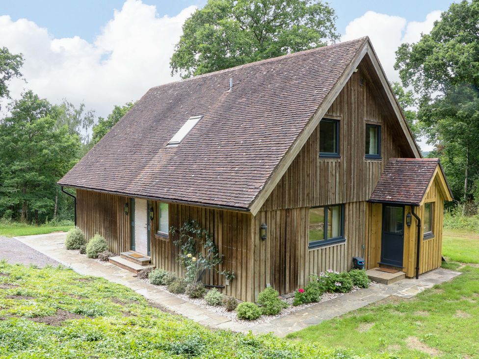 A house with wooden exterior and garden at Lakeside Lodge in Witherenden Hill near Burwash