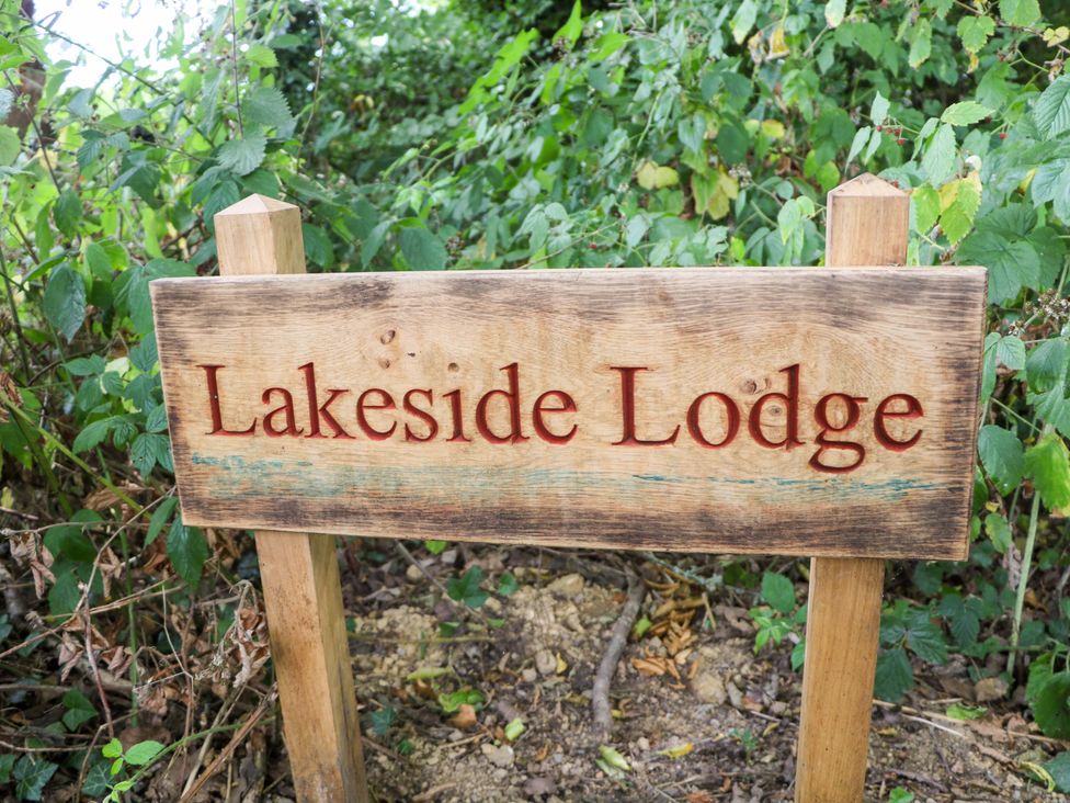 A wooden sign reading Lakeside Lodge surrounded by greenery