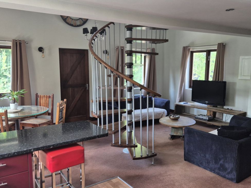 A living room with a spiral staircase and seating area at Flat 3, The Old Bakehouse in Telford