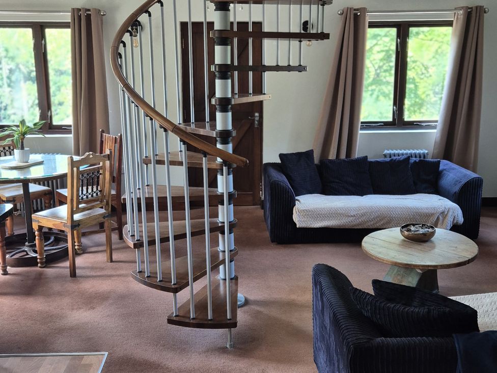 A living room with a spiral staircase and seating in Flat 3, The Old Bakehouse Telford