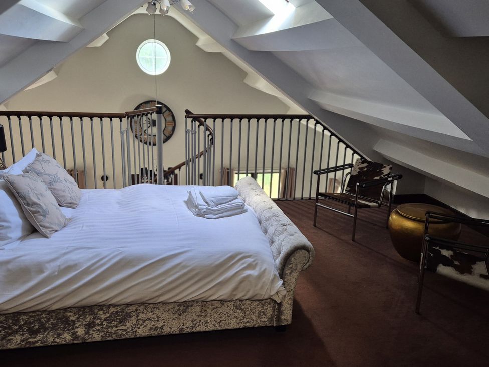 A bedroom with a bed and armchairs at Flat 3, The Old Bakehouse in Telford