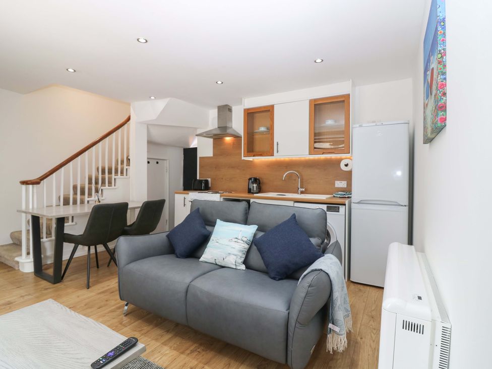 A living room with a sofa and kitchenette at 3 Caroline Place Fraserburgh