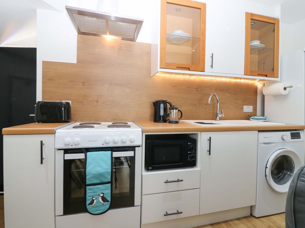 A kitchen with appliances including a microwave and washing machine at 3 Caroline Place in Fraserburgh