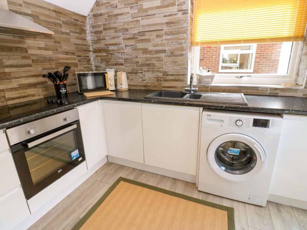 A kitchen with a microwave, washing machine, and oven at 8 Shearwater Way in Blyth