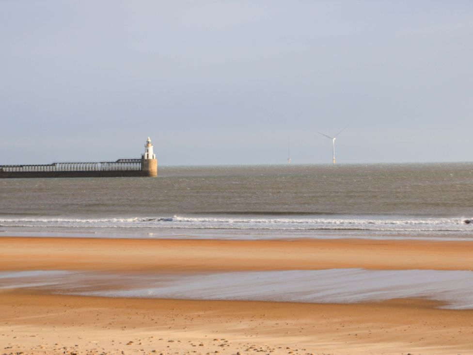 A view of a pier with a lighthouse and wind turbines in the distance at 8 Shearwater Way Blyth