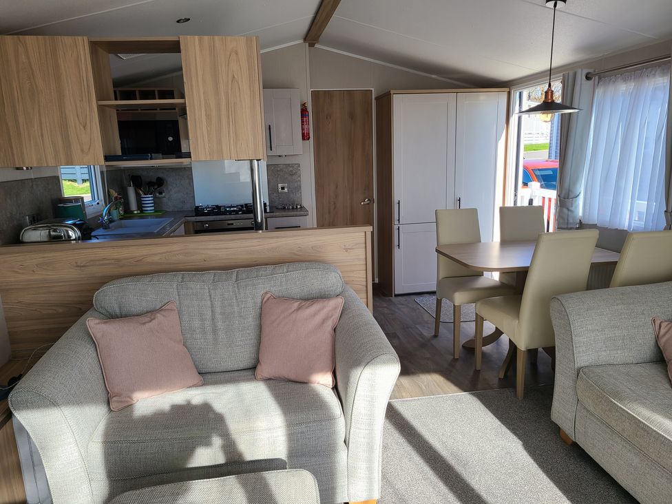 A living room with a sofa and dining area at The Maples, no. 56 St. Austell
