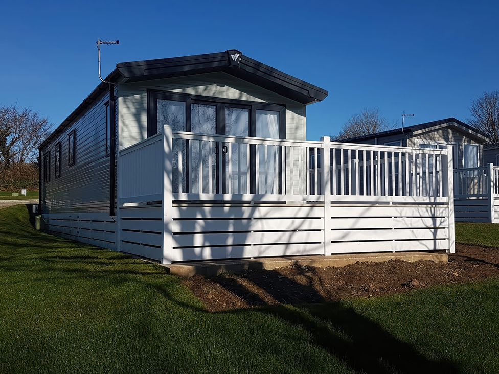 A mobile home with a deck and fence at The Maples, no. 56 St. Austell