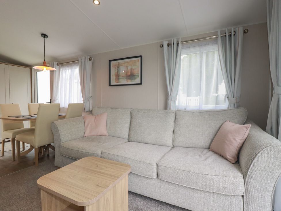 A living room with a sofa and dining area at The Maples, no. 56 Hewas Water near Polgooth