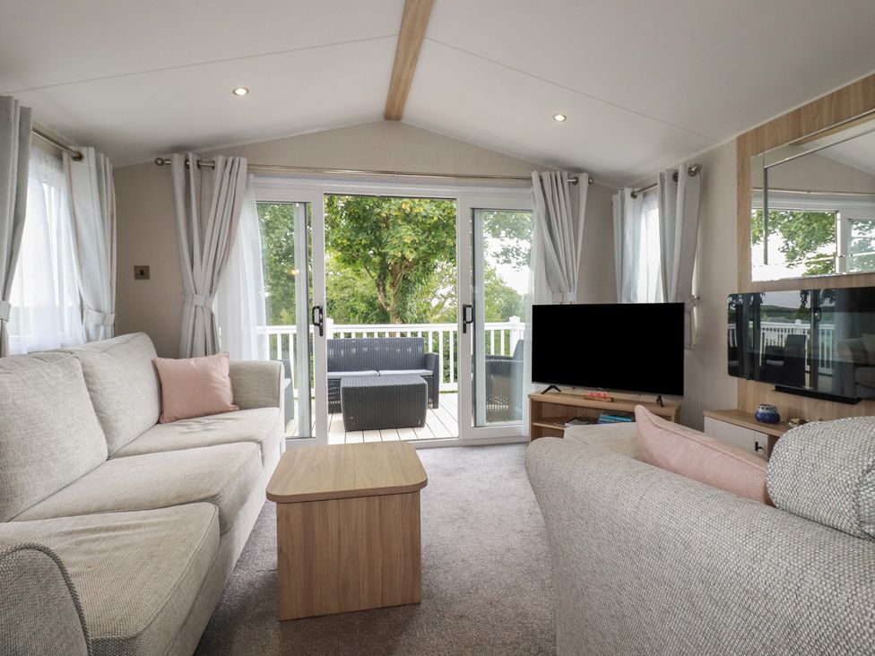 A living room with a sliding door leading to a deck at The Maples, no. 56 Hewas Water near Polgooth