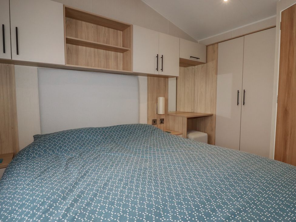 A bedroom with a bed and shelves at The Maples, no. 56 Hewas Water near Polgooth