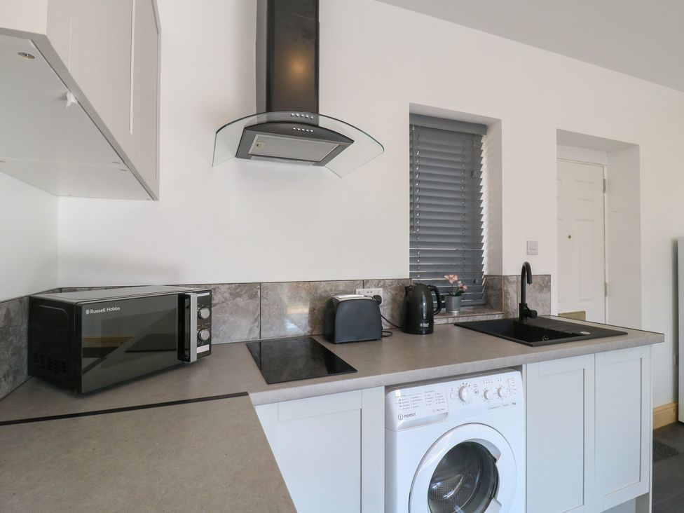 A kitchen with appliances including microwave and washing machine at Annex studio 2 Northampton