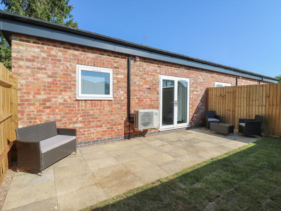 An outdoor area with patio furniture and a brick wall at Annex studio 2 Northampton