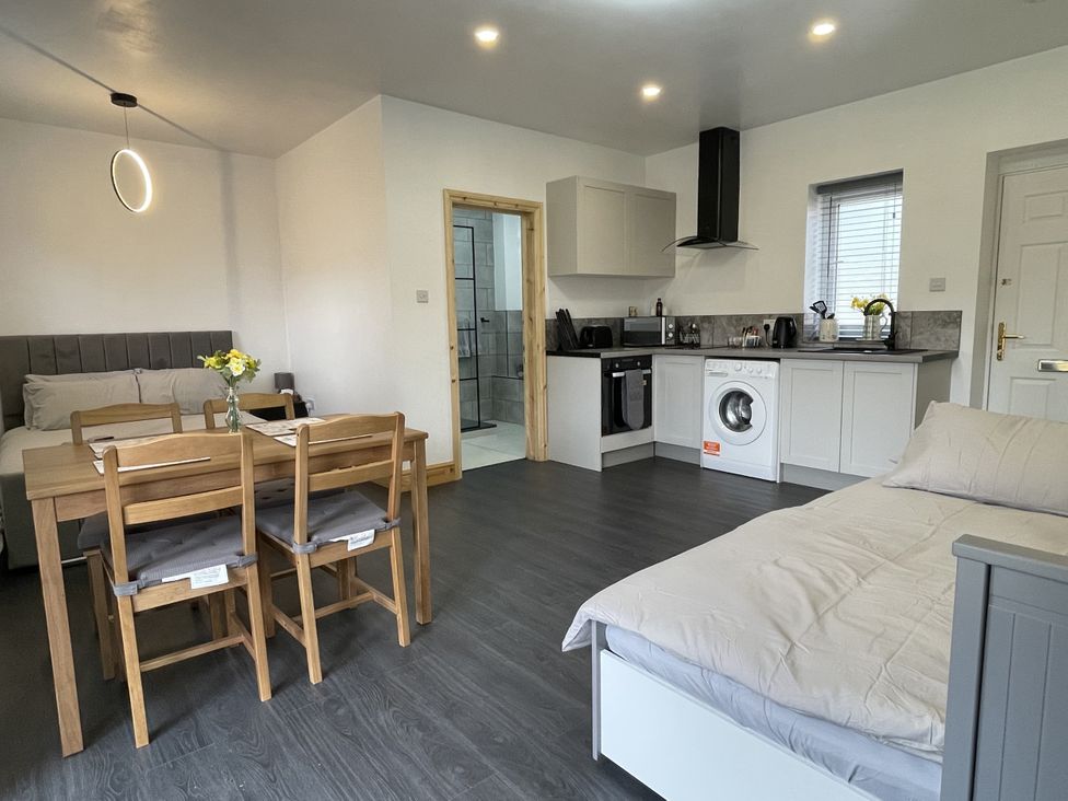 A living room with a sofa dining table and kitchen units at Daffodil Northampton