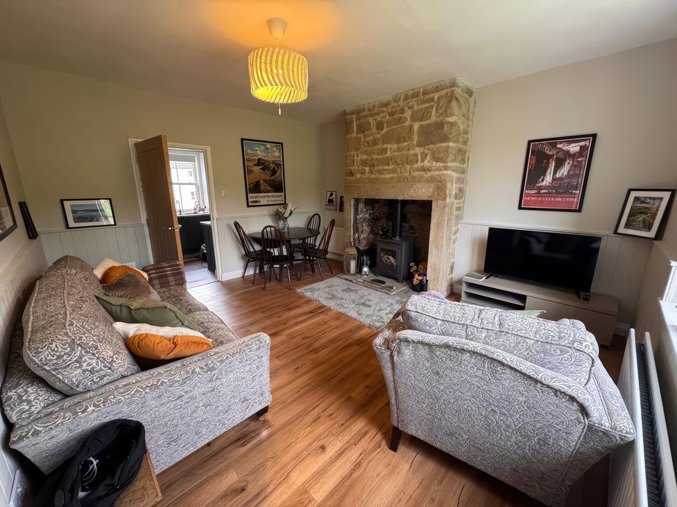 A living room with a sofa and dining table at Old Station Cottage in Hexham