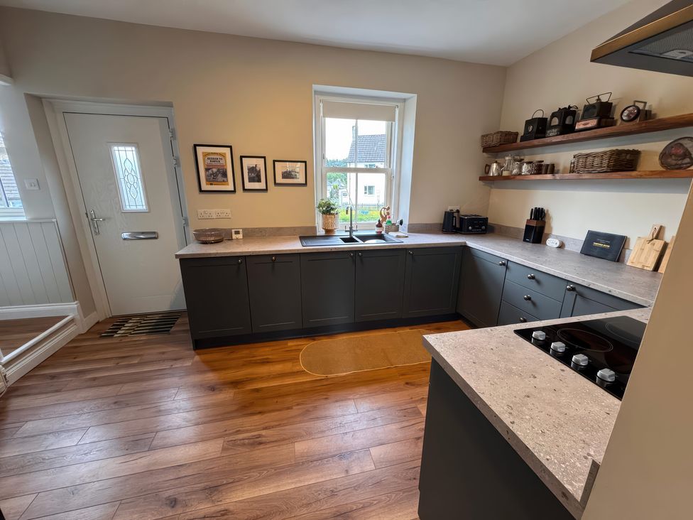 A kitchen with countertop, sink, and shelves at Old Station Cottage in Hexham