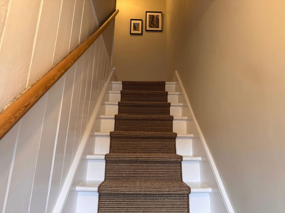A staircase with a handrail and picture frames at Old Station Cottage in Hexham