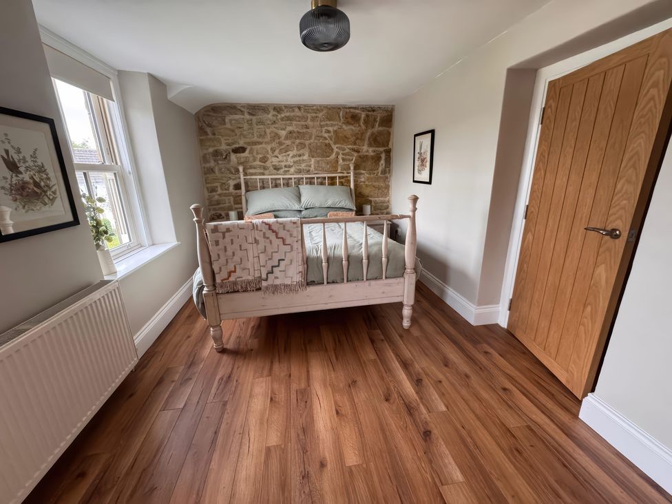 A bedroom with a bed and stone wall at Old Station Cottage in Hexham