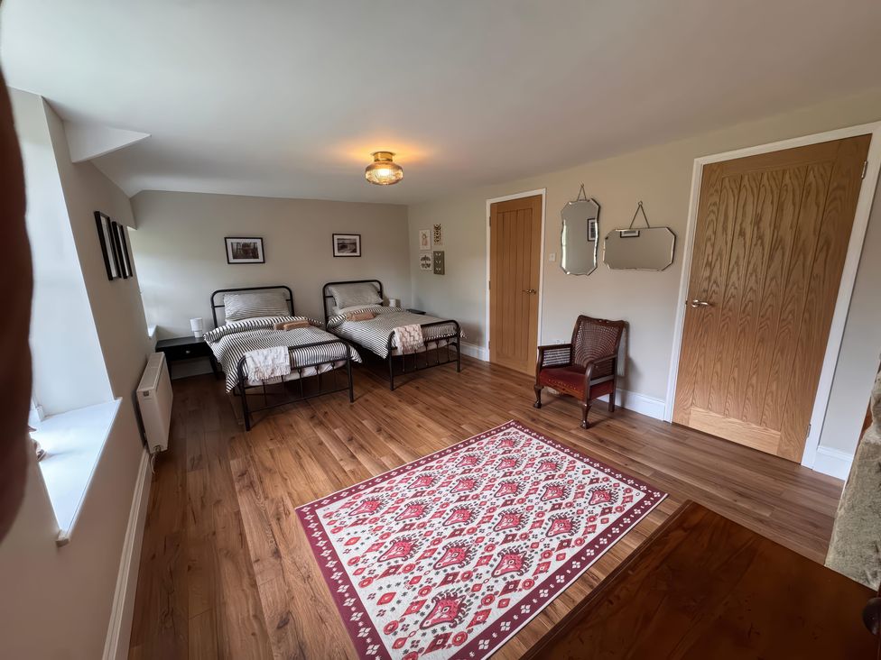 A bedroom with two beds and a chair at Old Station Cottage in Hexham