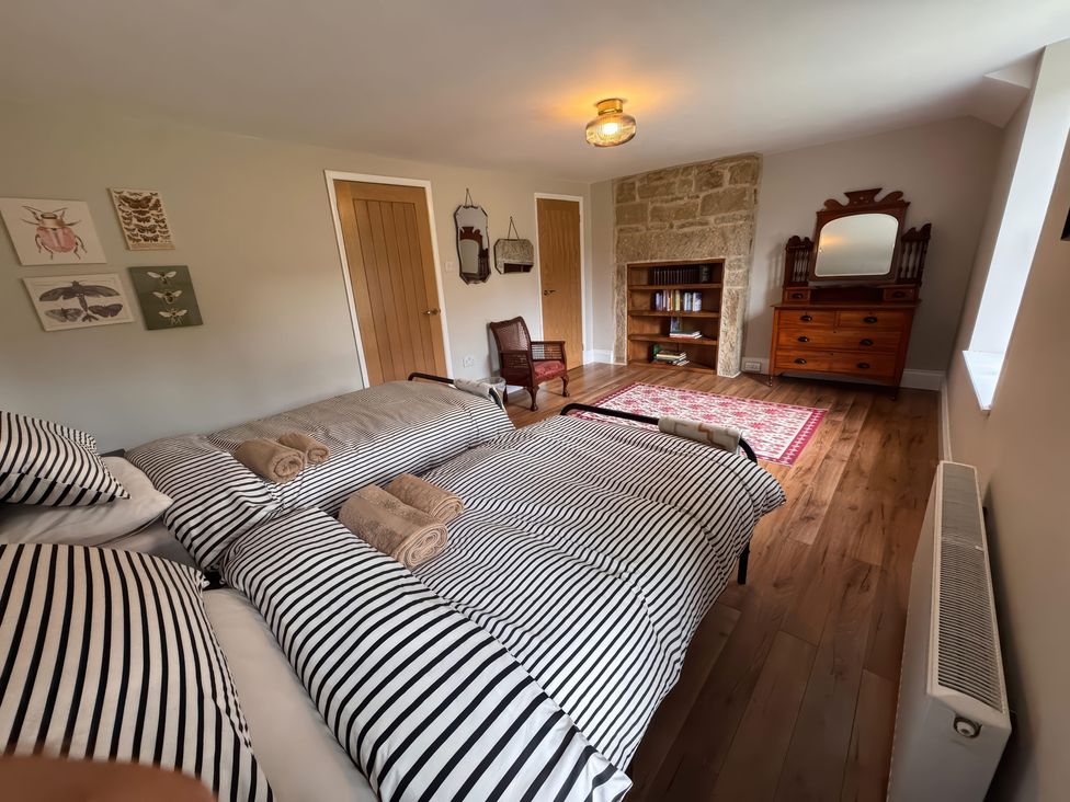 A bedroom with a bed and bookshelf at Old Station Cottage in Hexham