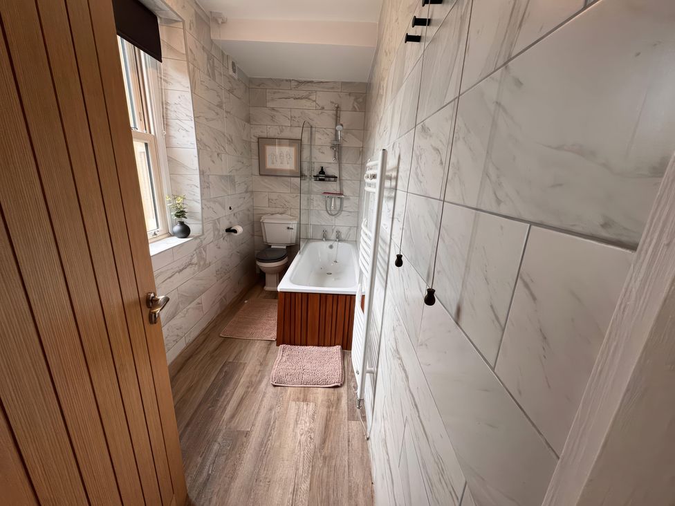 A bathroom with a bathtub, toilet, and sink at Old Station Cottage in Hexham