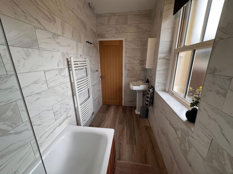 A bathroom with a bathtub, sink and towel radiator at Old Station Cottage in Hexham