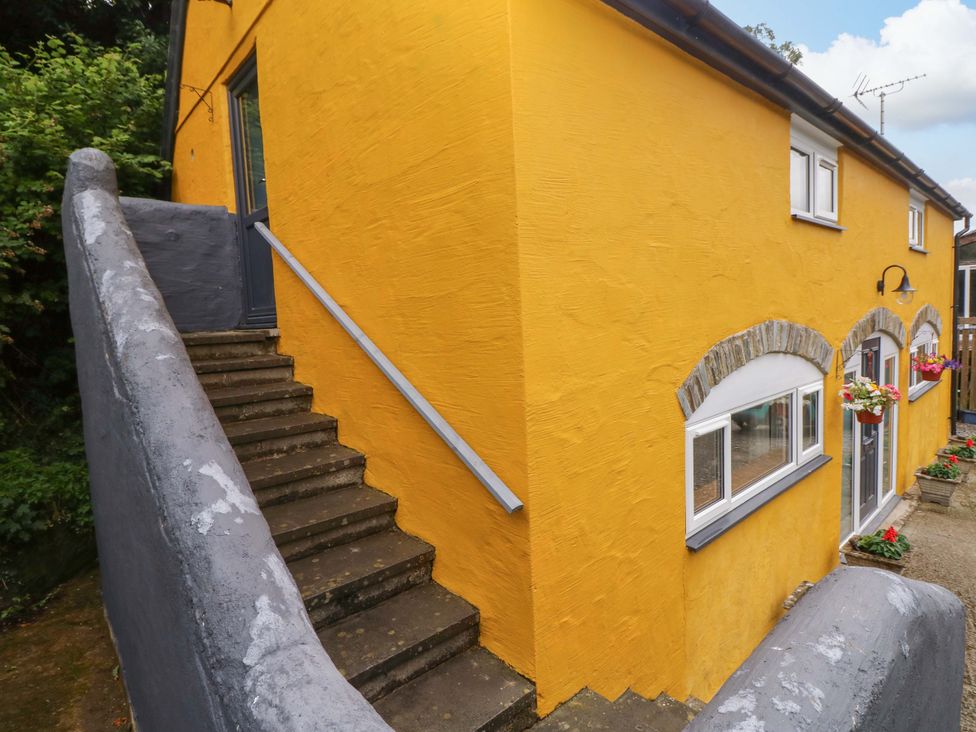 An exterior view of a yellow building with a staircase and doorway at Pendre Barn Llanfyrnach