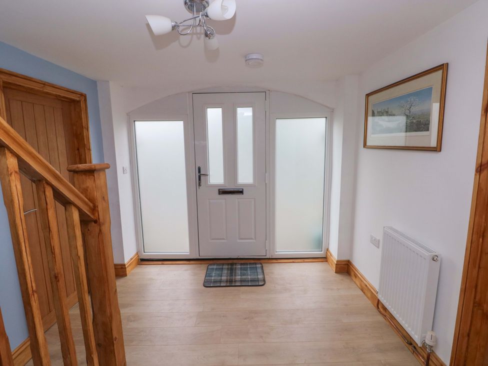 A hallway with a front door and staircase at Pendre Barn Llanfyrnach