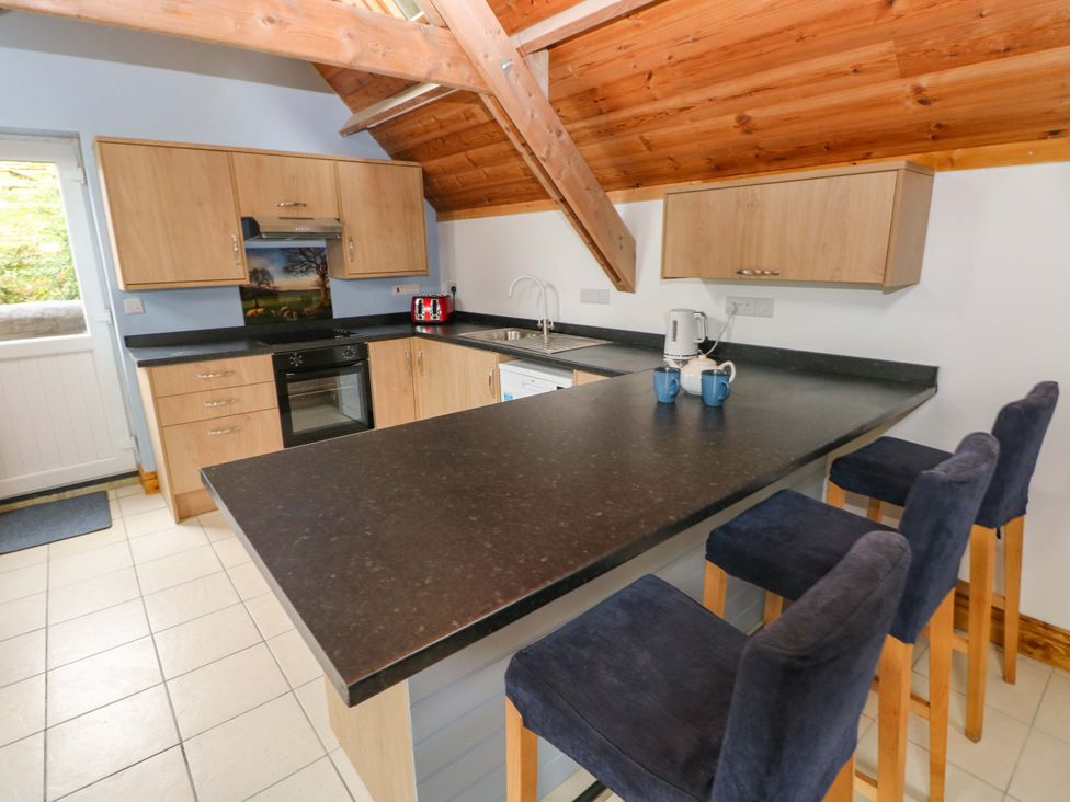 A kitchen with cabinets and bar stools at Pendre Barn Llanfyrnach