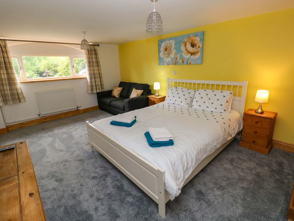 A bedroom with a bed and sofa at Pendre Barn in Llanfyrnach