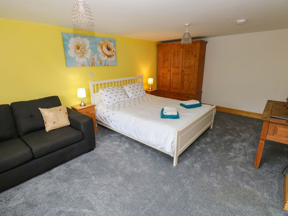 A bedroom with a bed and sofa at Pendre Barn in Llanfyrnach