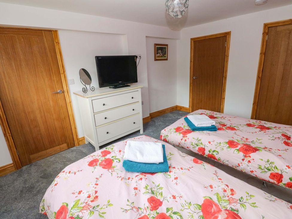 A bedroom with two beds and a television at Pendre Barn Llanfyrnach