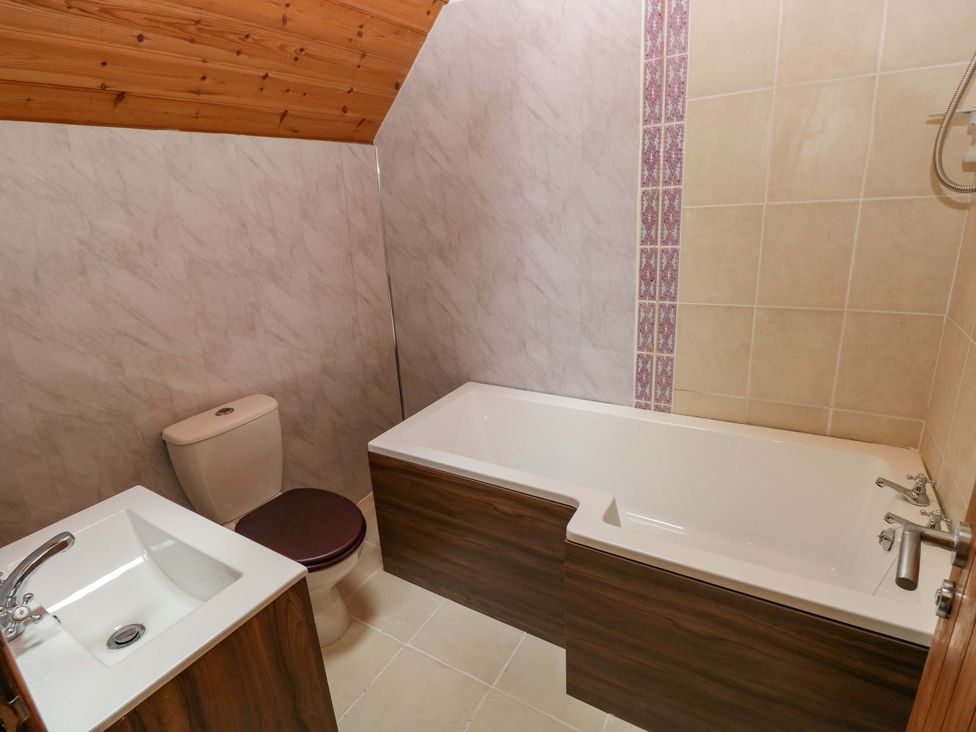 A bathroom with a bathtub, toilet and sink at Pendre Barn Llanfyrnach