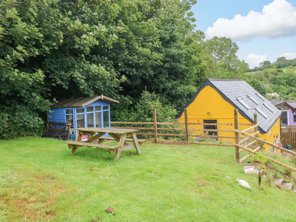 An outdoor area with a wooden table and a shed at Pendre Barn Llanfyrnach