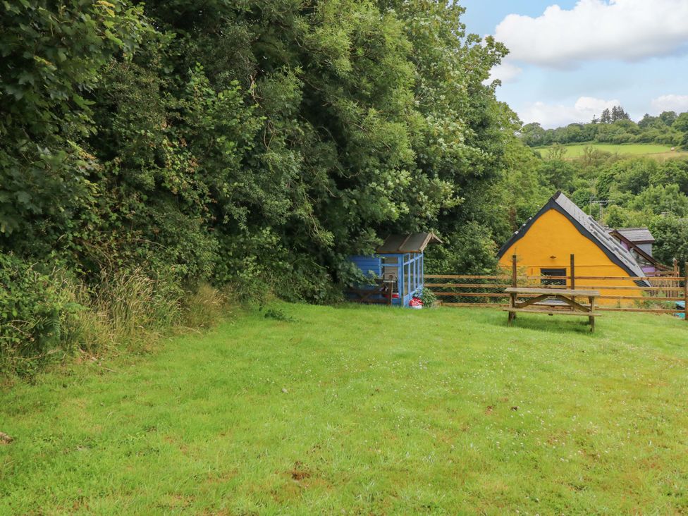 An outdoor area with a shed and a yellow house at Pendre Barn Llanfyrnach