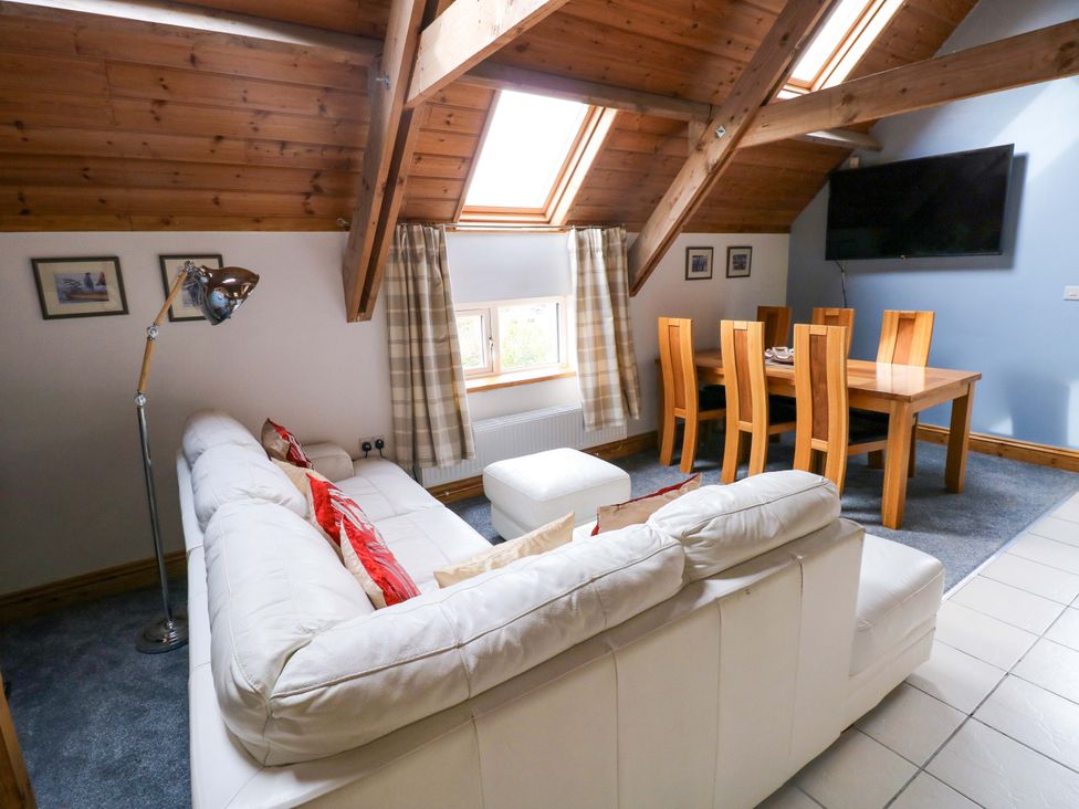 A living room with a sofa and dining area at Pendre Barn in Star near Cenarth