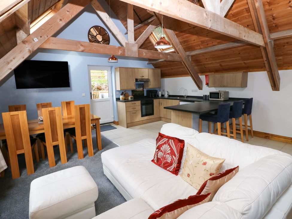 A living room with a sofa and dining area at Pendre Barn Star near Cenarth