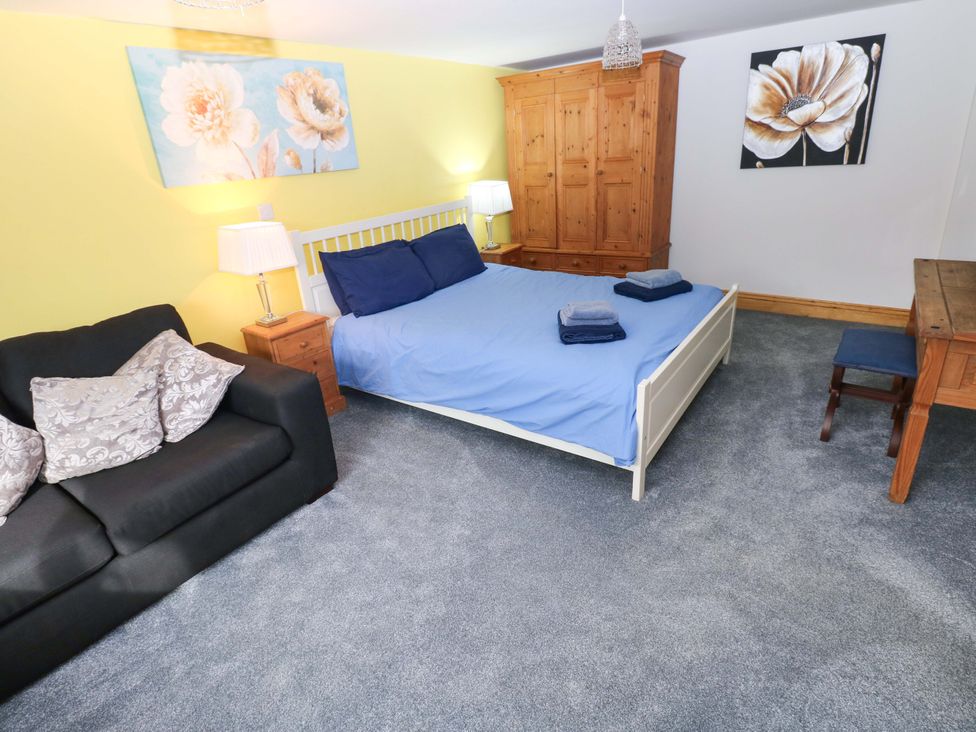 A bedroom with a bed, sofa, and wardrobe at Pendre Barn in Star near Cenarth