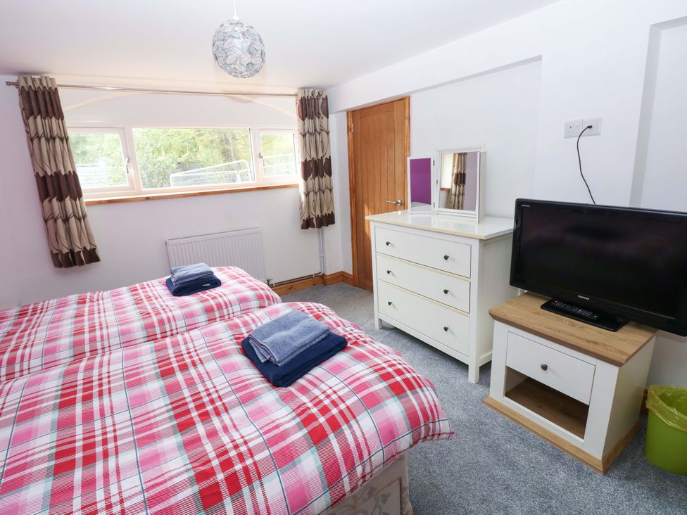 A bedroom with two beds and a television at Pendre Barn Star near Cenarth