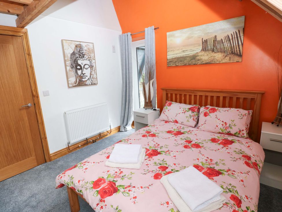 A bedroom with a bed and nightstands at Pendre Barn Star near Cenarth