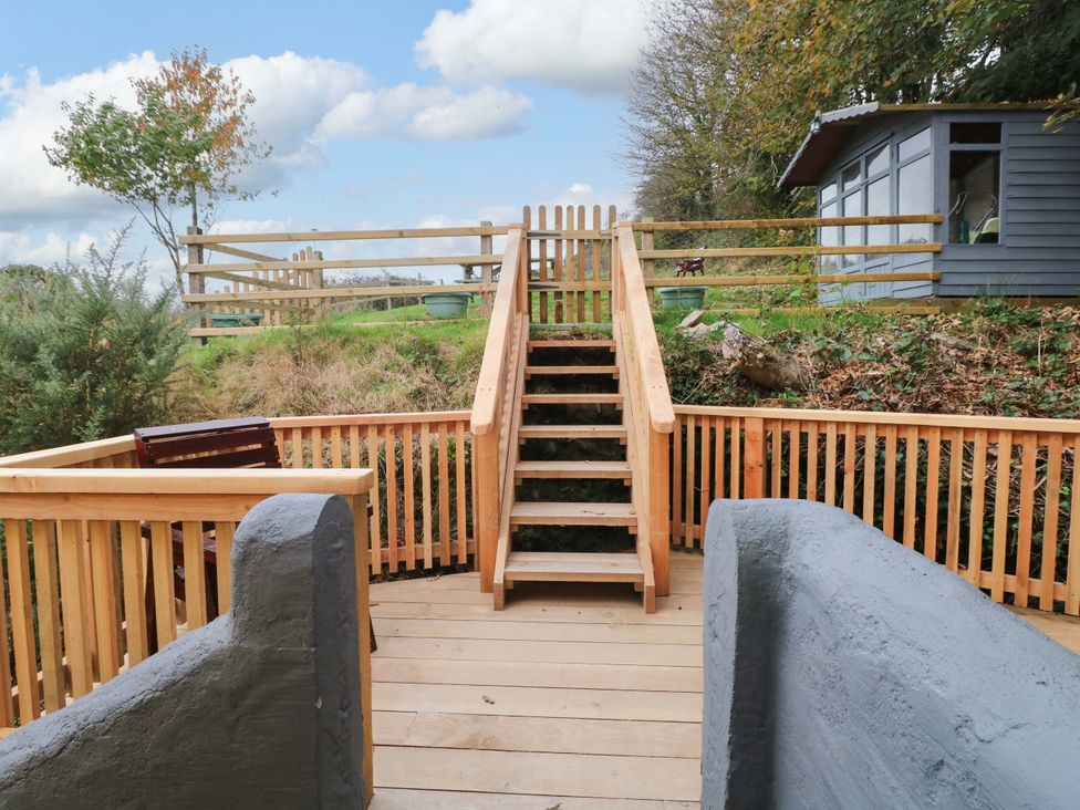 A wooden deck area with stairs leading to a fenced area at Pendre Barn Star near Cenarth