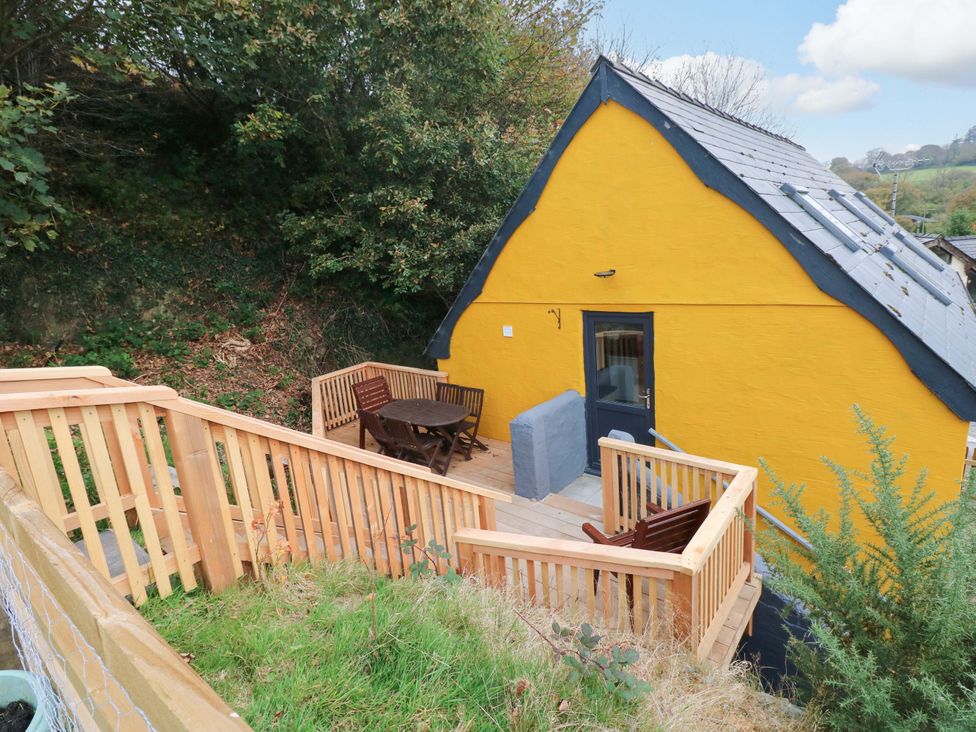 An outdoor deck with a yellow building at Pendre Barn Star near Cenarth